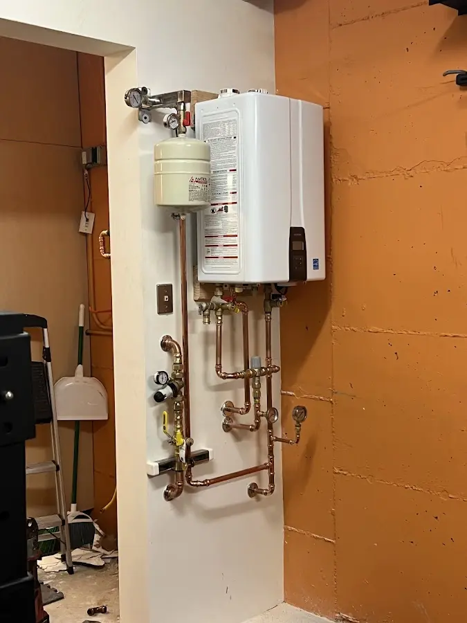 Plumbing technician inspecting water heater connections in Spirit Lake